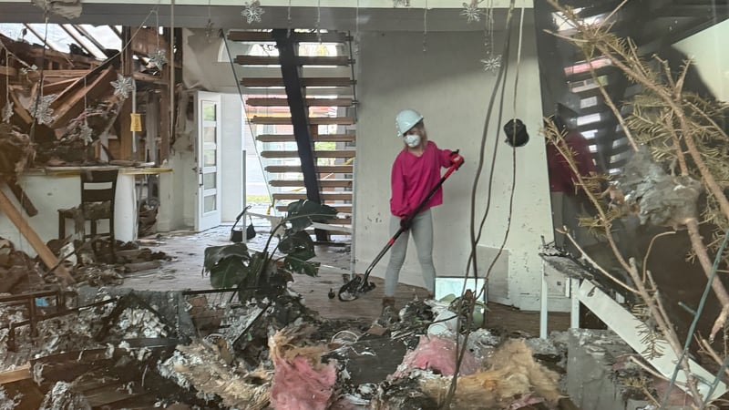 Siri Dahl in a hard hat and mask, standing in a fire-damaged room